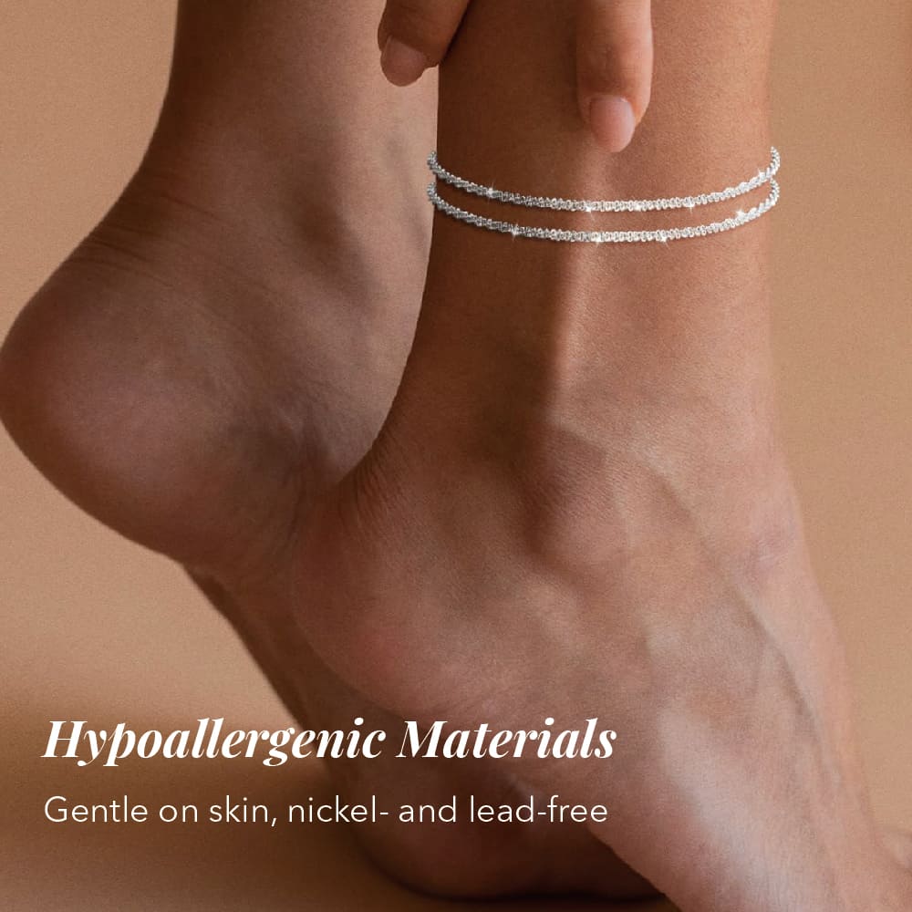 Silver anklets on a person's ankle with a beige background and text about hypoallergenic materials.